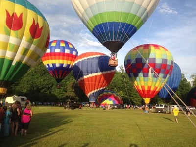 6 hot air ballons on the ground getting ready for take off