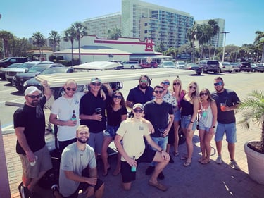 A bunch of people taking a picture in front of a golf cart on a pub crawl