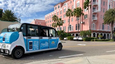 Blue electric car out side a pink hotel