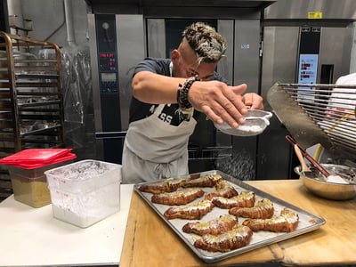 Man putting powdered sugar on crosants