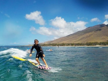 Young boy surfing a wave in Maui