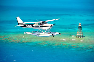 blue and white seaplane flying over the ocean