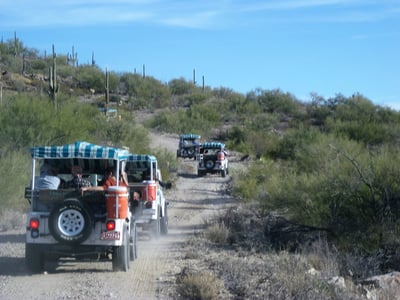 four jeeps driving on a dusty road in tucson