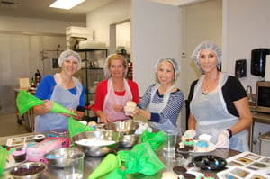 four ladies with hair nets on in cooking class