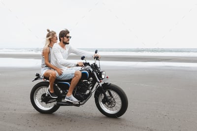 man and women on a motorcycle on the beach