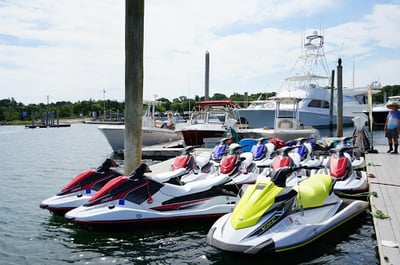 red, yellow and blue jet skis in the water for rent