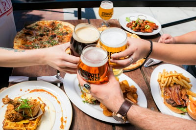 three people sharing beer and food