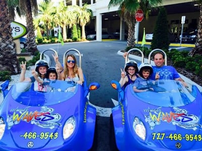 two blue mini cars with 3 people in each