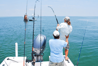 two people fishing on the back of a boat