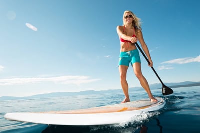 women in blue shorts on a paddle board