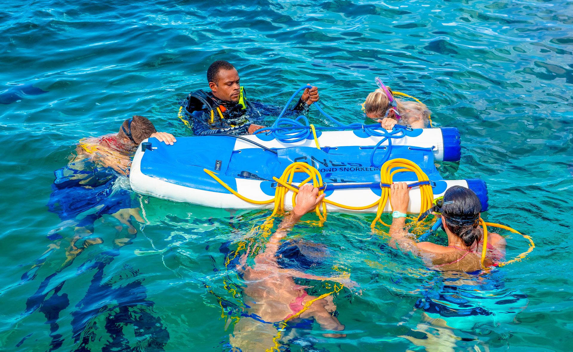 5 people hanging on a raft getting ready to Snuba