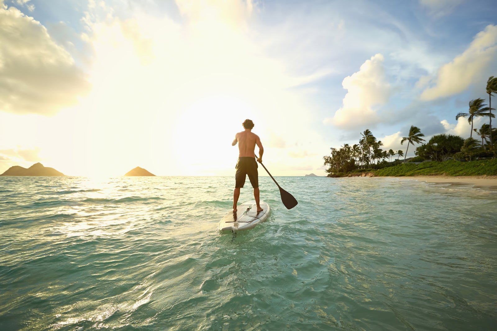 Man paddleboarding at sunset