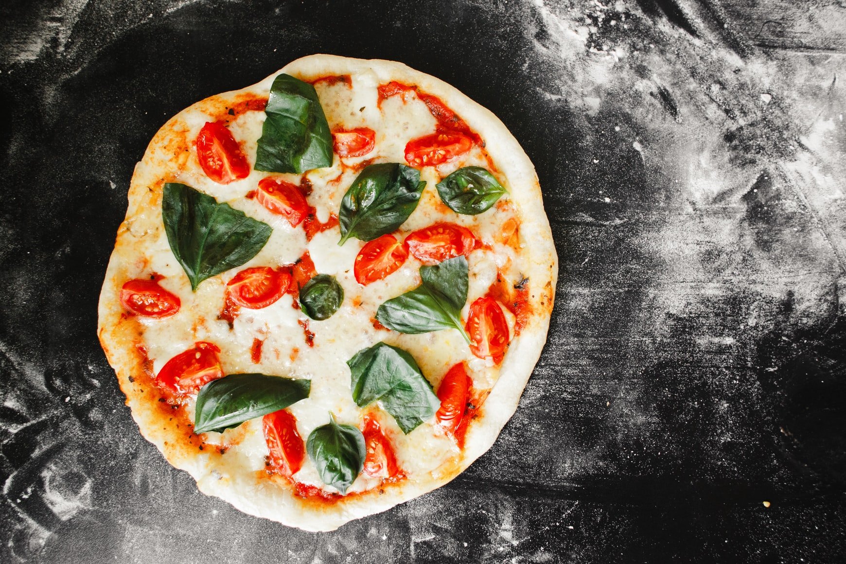 Margarita pizza on black block of wood