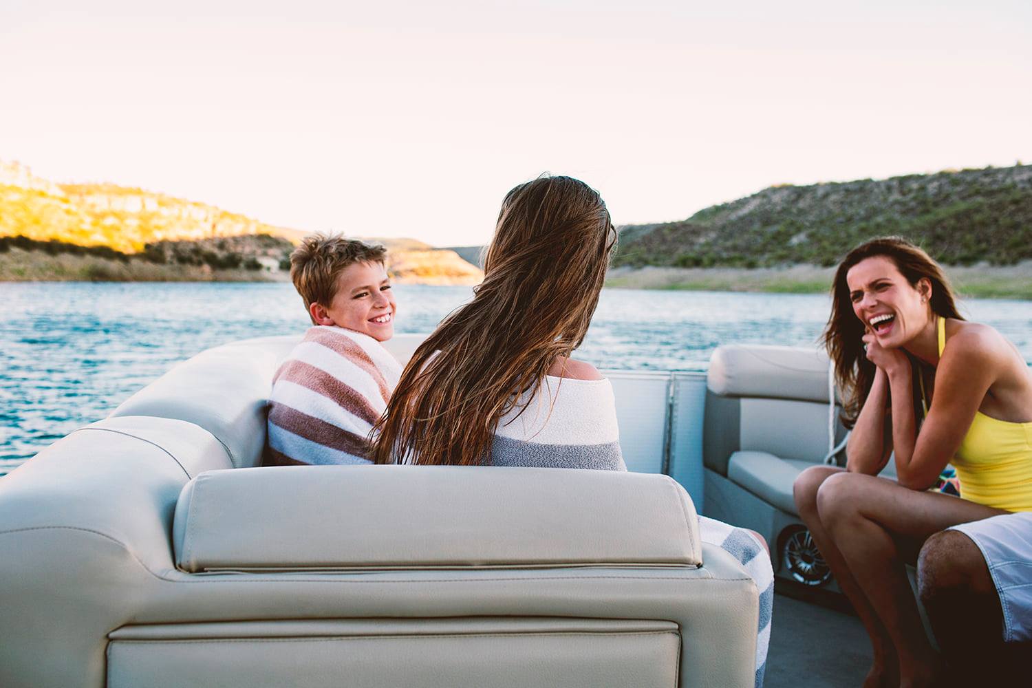 Three people sitting on a pontoon boat enjoying the water