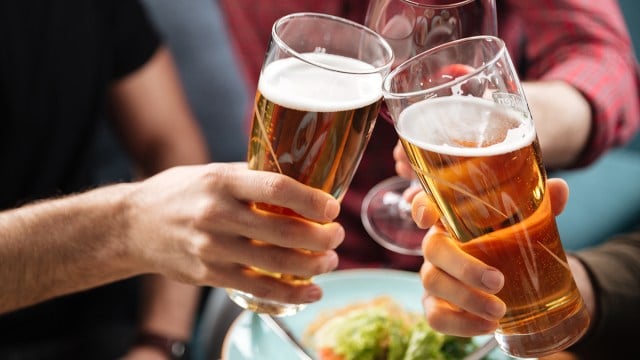 Three people cheering with beer