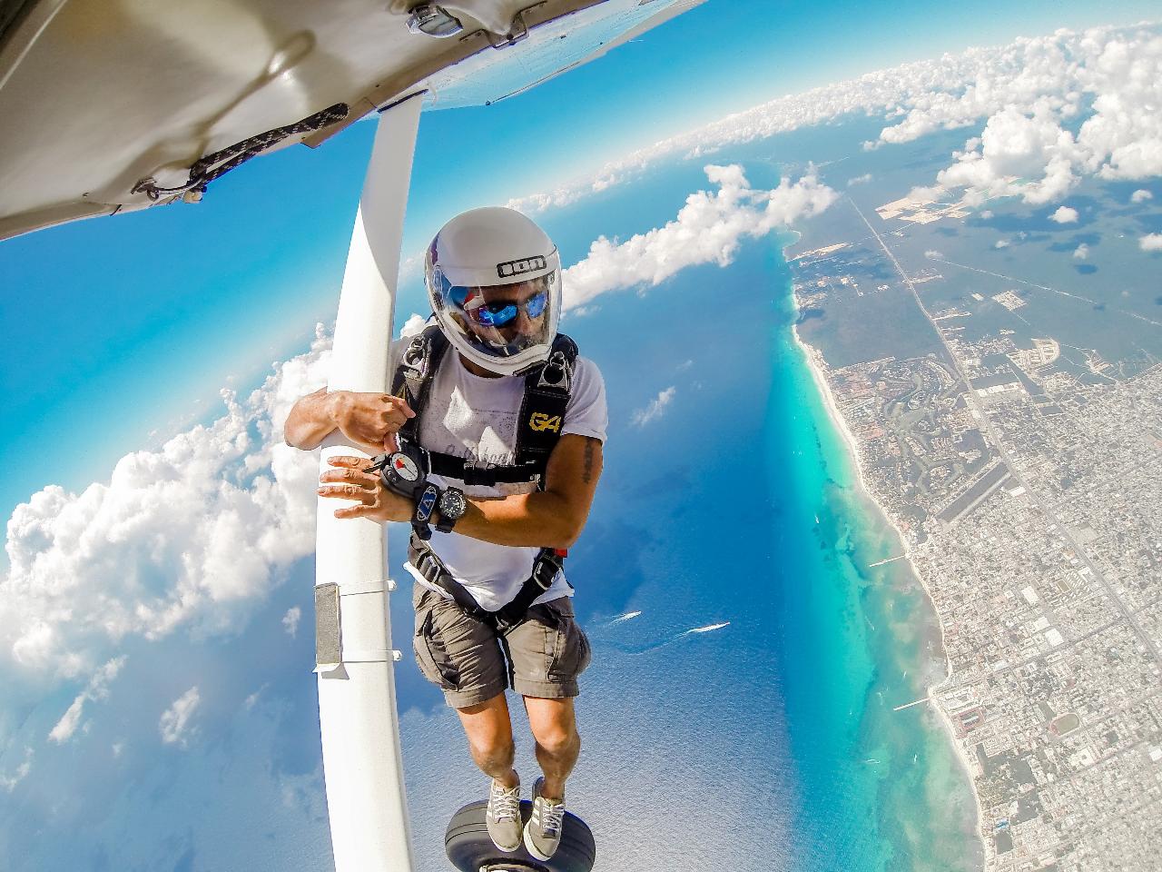 man standing on the wheel of a plane before he jumps skydiving