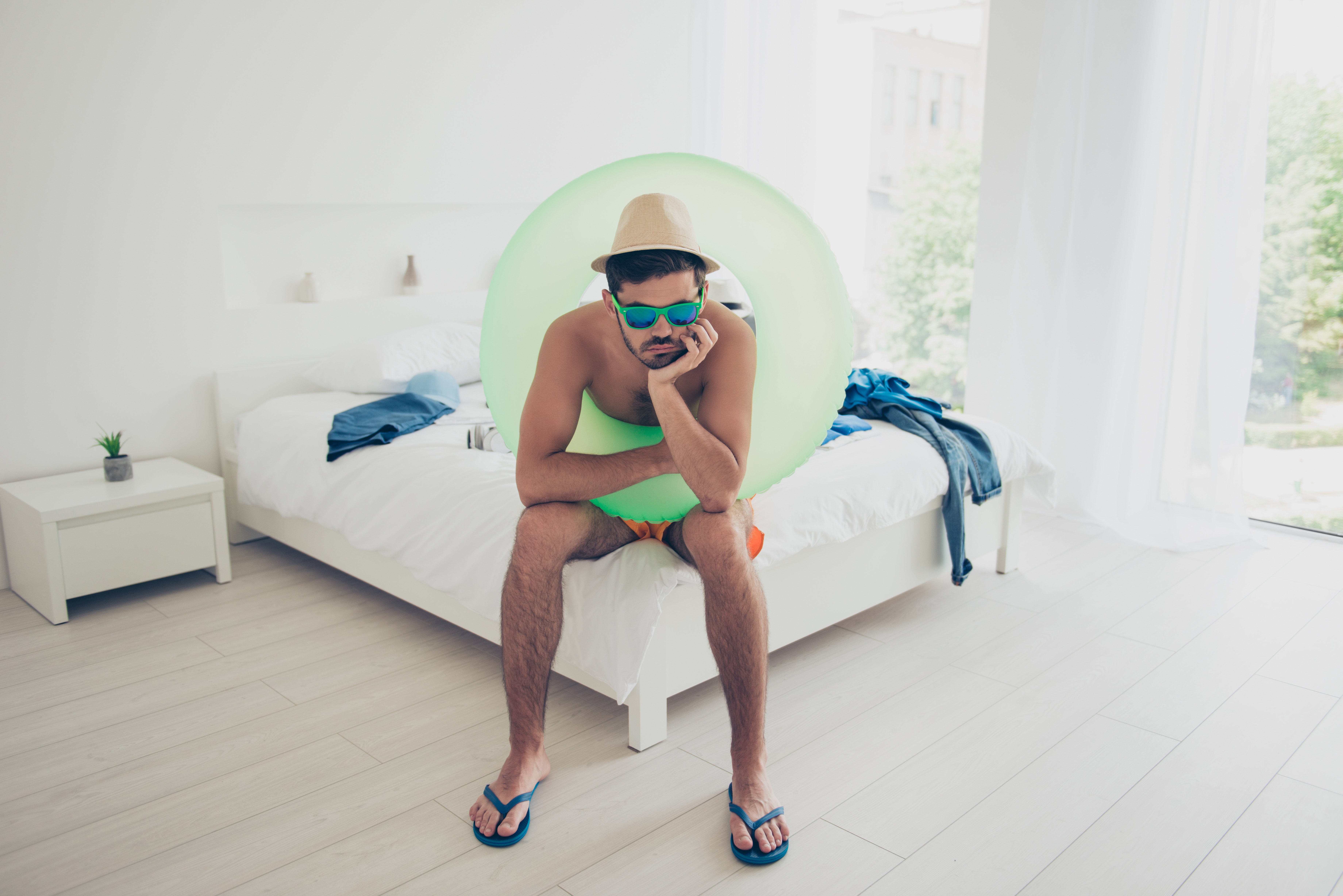 Man sitting on his bed in a lime green pool tube